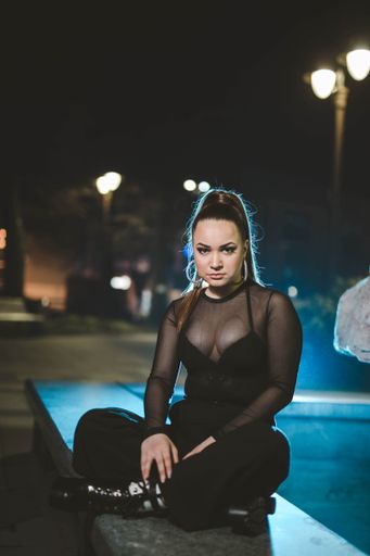 A sexy female from Bosnia and Herzegovina in a black transparent shirt sitting and posing at camera