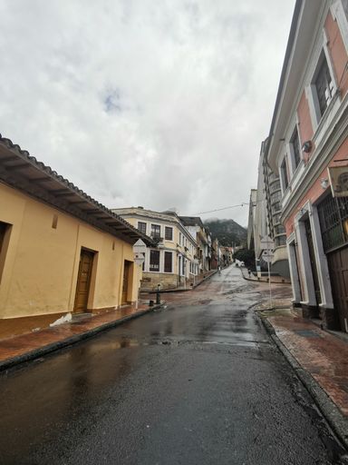 A vertical shot of a road surrounded by residential buildings on a rainy day in Bogota, Colombia