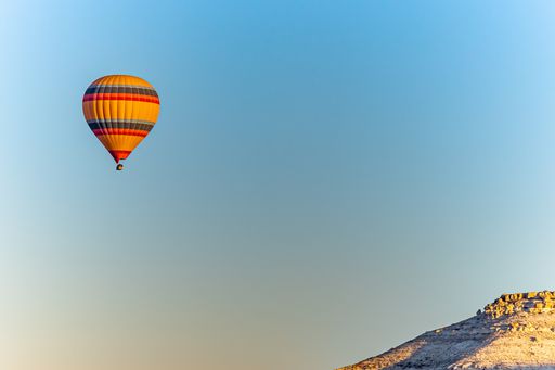 A colorful hot-air balloon flying over the Cappadocia region in Turkey in a blue sky