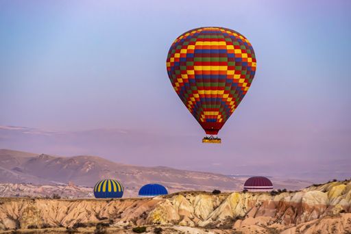 A view of colorful hot-air balloons flying over the Cappadocia region in Turkey in a blue and pink sky