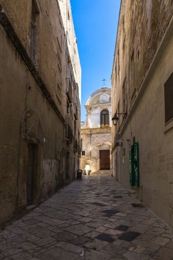 A vertical shot of a corridor between the old historic buildings in the Monopoli historic center, Apulia, Italy