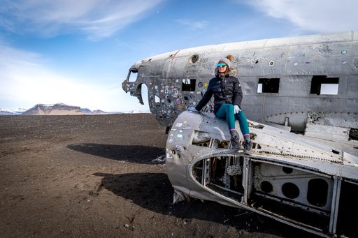 A young female traveler sits in an airplane cabin while her journey is paused, looking off into the distance with a contemplative expression
