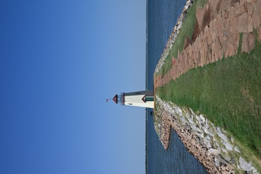 A vertical of a lighthouse on a pier on a sunny day