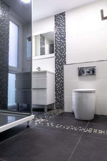 a vertical shot of a modern toilet in white and gray colors with a shower cabin