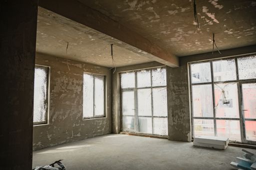 an indoor construction site with big windows, concrete walls and ground