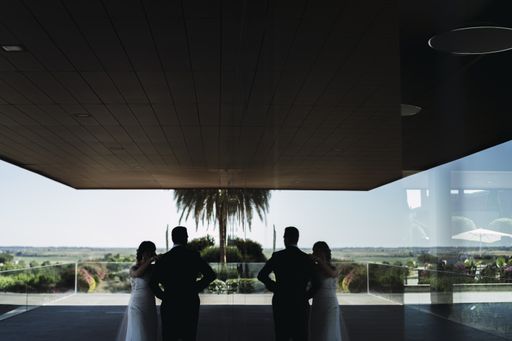 The groom and bride posing at the balcony with their reflection mirrored in the window