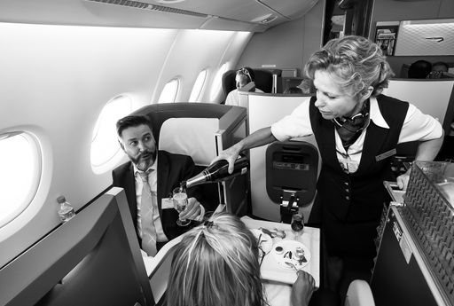 Johannesburg, South Africa - February 06 2014: Female cabin crew pouring a glass of champaign in business class of an Airbus A380