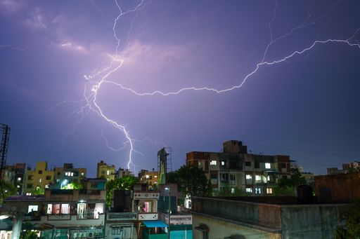 The moment of a massive lightning strike on the purple sky at night over the city