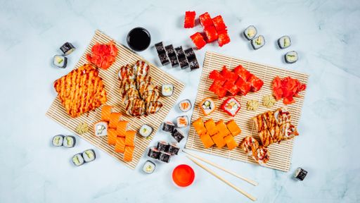 A top view of different types of sushi rolls served with soy sauce, ginger and wasabi