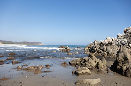 A landscape of the sea surrounded by the sea and rocks under the sunlight and a blue sky in Mexico