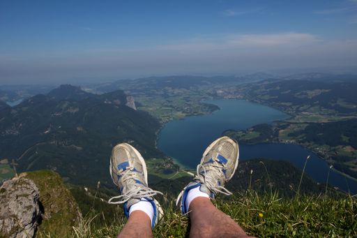 A selective focus shot of a traveler's feet in the high above the Wolfgangsee Lake in Austria
