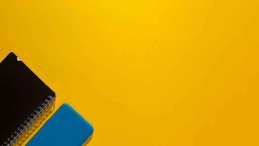 A top view of a smartphone and a notepad on a yellow background