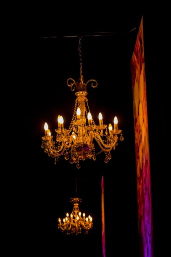 A vertical shot of hanging illuminated chandeliers in a dark room