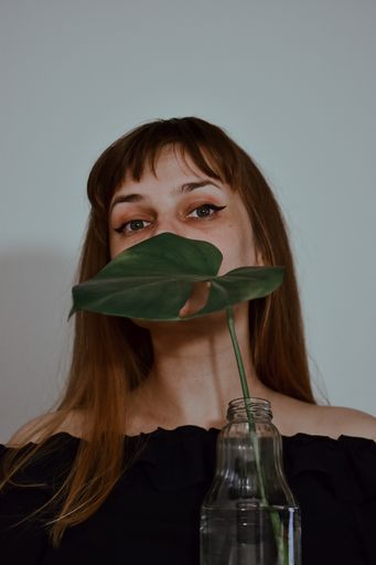 A vertical shot of a caucasian female posing with a green plant in a glass jar