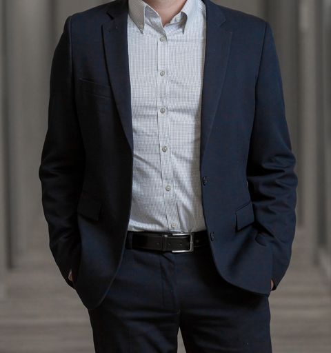 An unrecognizable businessman with a classic suit standing with hand in his pockets