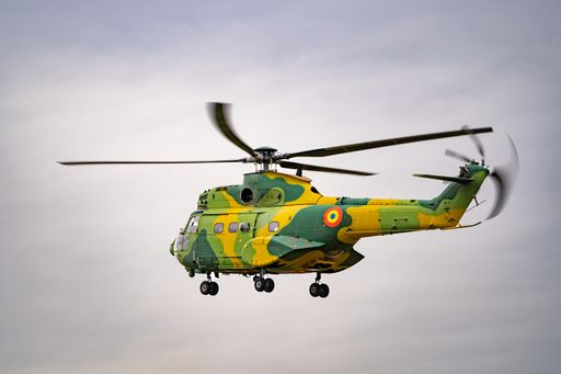 A closeup of a green and yellow helicopter soaring through a cloudy sky