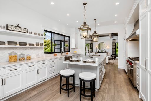 A modern kitchen interior featuring white cabinets and stainless steel appliances set on a wooden floor