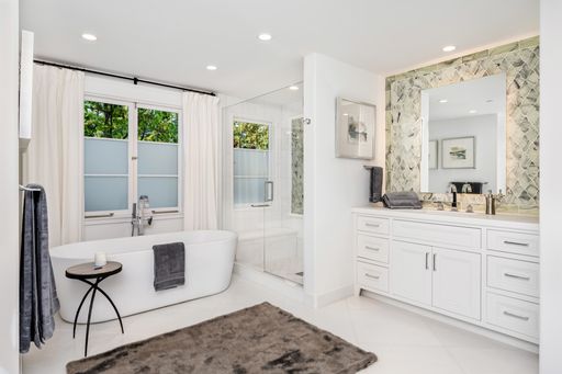 A pristine white bathroom with a large, luxurious bathtub and a window that allows natural light to enter the room