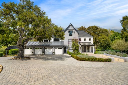 A sprawling ranch-style home is nestled in a spacious, tree-lined yard, providing a peaceful and private atmosphere