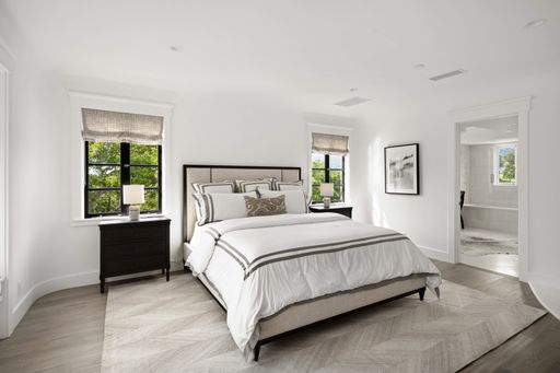 A modern bedroom with white walls, grey accents and flooring