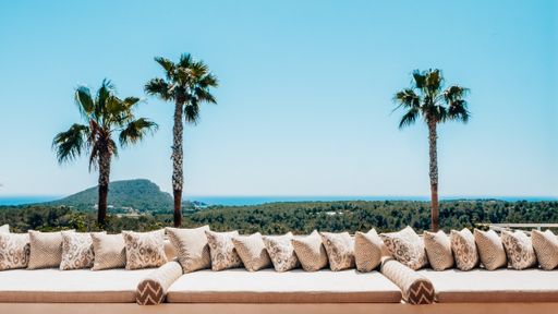 A white, sun-drenched sundeck situated among a lush tropical oasis in Ibiza, Spain