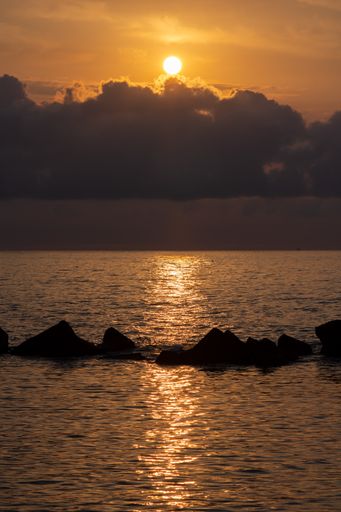 A vertical shot of the sea under a cloudy sky during a beautiful sunset in the evening