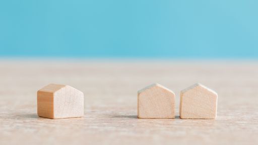 Three miniature wooden houses on a table - real estate and housing property market concept