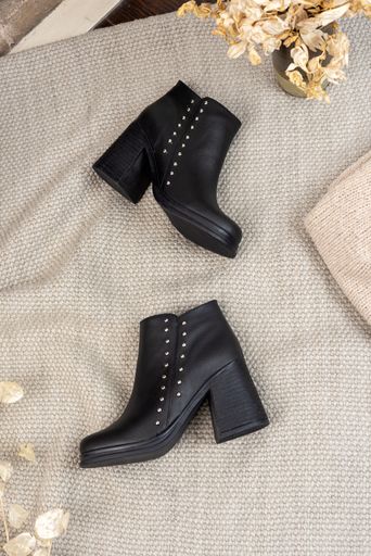 A vertical shot of black leather female boots in a showroom