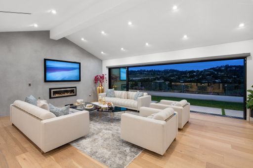 This contemporary living room showcases two stylish sofas and two end tables next to a large window, providing an abundance of natural light