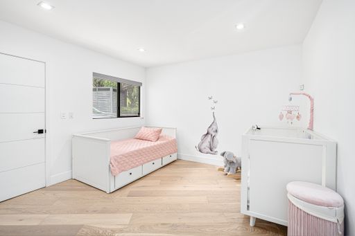 A cozy bedroom features a white-painted wall, twin-size bed, and wood flooring, creating a warm and inviting atmosphere