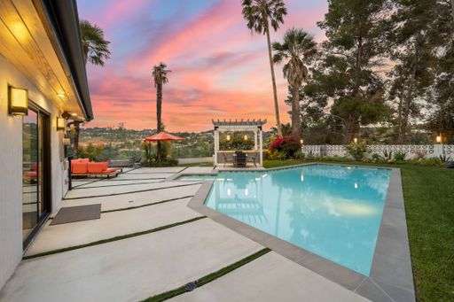 An outdoor residential pool surrounded by a lush, verdant lawn