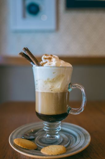 A cappuccino with cookies and cinnamon on a wooden table