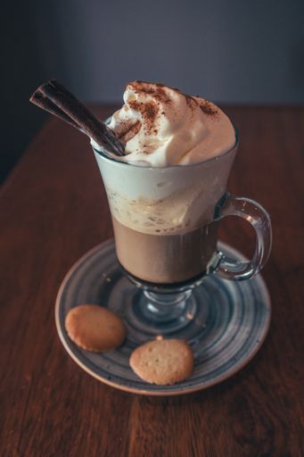 A cappuccino with cookies and cinnamon on a wooden table
