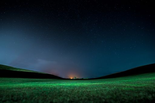 A beautiful landscape with a green field under the starry night sk