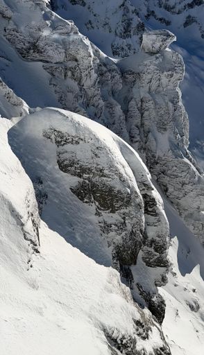 A male skier in a blue ski outfit skiing down the side of a snow-covered mountain
