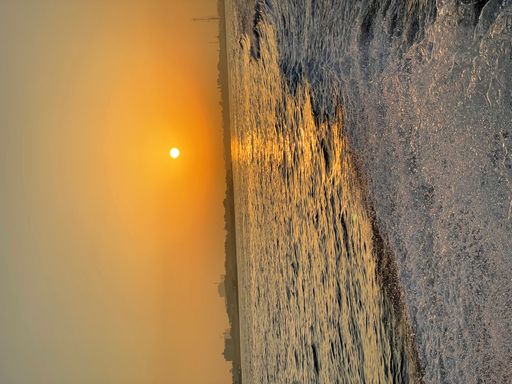 Spectacular sunset over the ocean with rolling waves crashing against the shoreline
