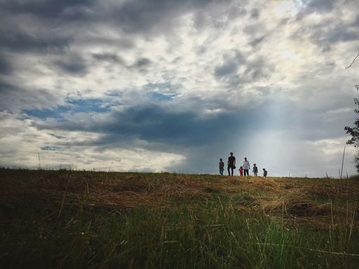 A wide angle shot of several people walking on the grass under a clouded sky