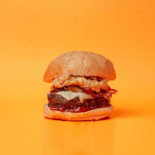 A mouthwatering, medium-sized beef burger set against a yellow backdrop.
