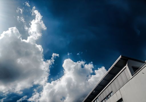 A low angle shot of the side of a concrete building under a beautiful cloudy sky