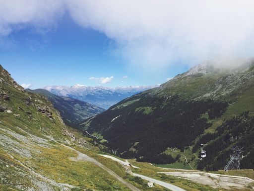 A high angle shot of a beautiful green landscape with high rocky mountains under a cloudy sky
