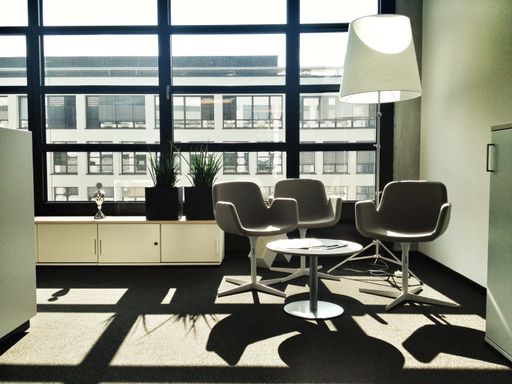 An empty office with a table and chairs with the view of tall buildings in the background