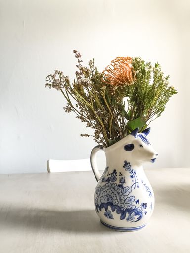 A vertical shot of a beautiful flower composition in a white vase on a white table