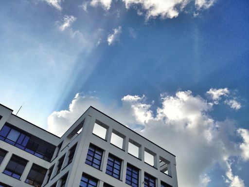 A low angle shot of a beautiful modern building in a glass facade under a cloudy sky