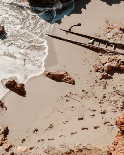 An aerial view of calm sea and footprints in the sand at Beach Cala Saladeta, Ibiza, Spain