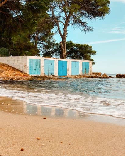 The calm sea and beautiful fishermen's huts at Beach Cala Pada, Ibiza, Spain