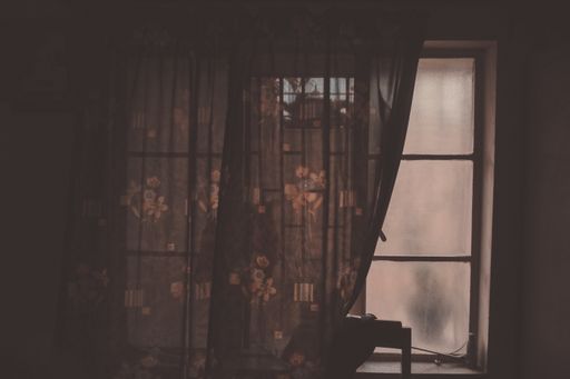 A closeup shot of a dark interior with old window and curtains