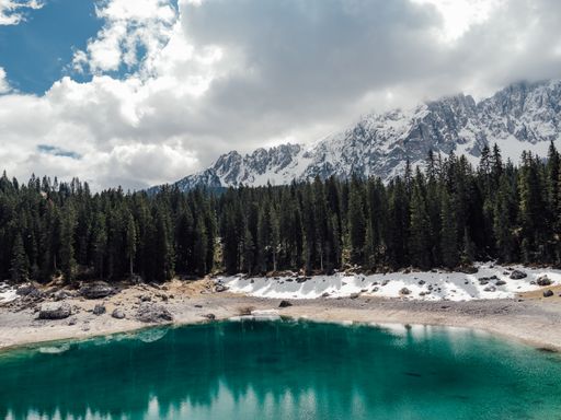 A stunning view of an alpine lake surrounded by snow-covered mountains and lush evergreen trees