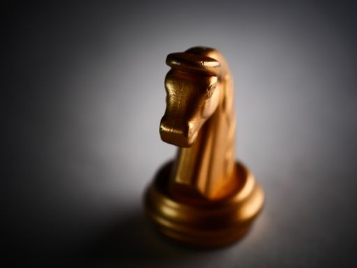 A closeup shot of a single golden knight chess piece