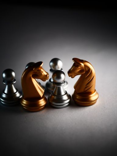 A vertical closeup shot of metallic gold and silver chess pieces