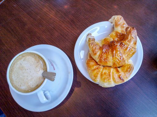 A high angle shot of a delicious coffee with fresh croissants on a white plate